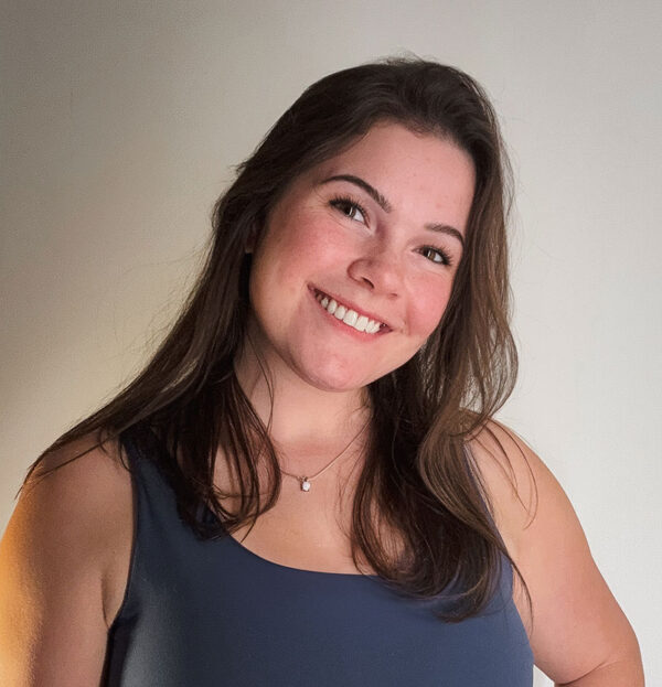 Laken Ellis, Project Designer at Solos Energy, smiling with long hair and a blue top, showcasing a friendly demeanor in a professional setting.