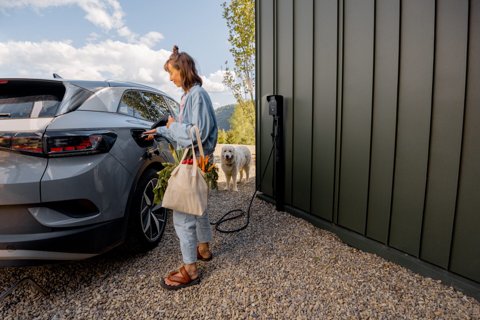 Woman charging electric car with dog nearby